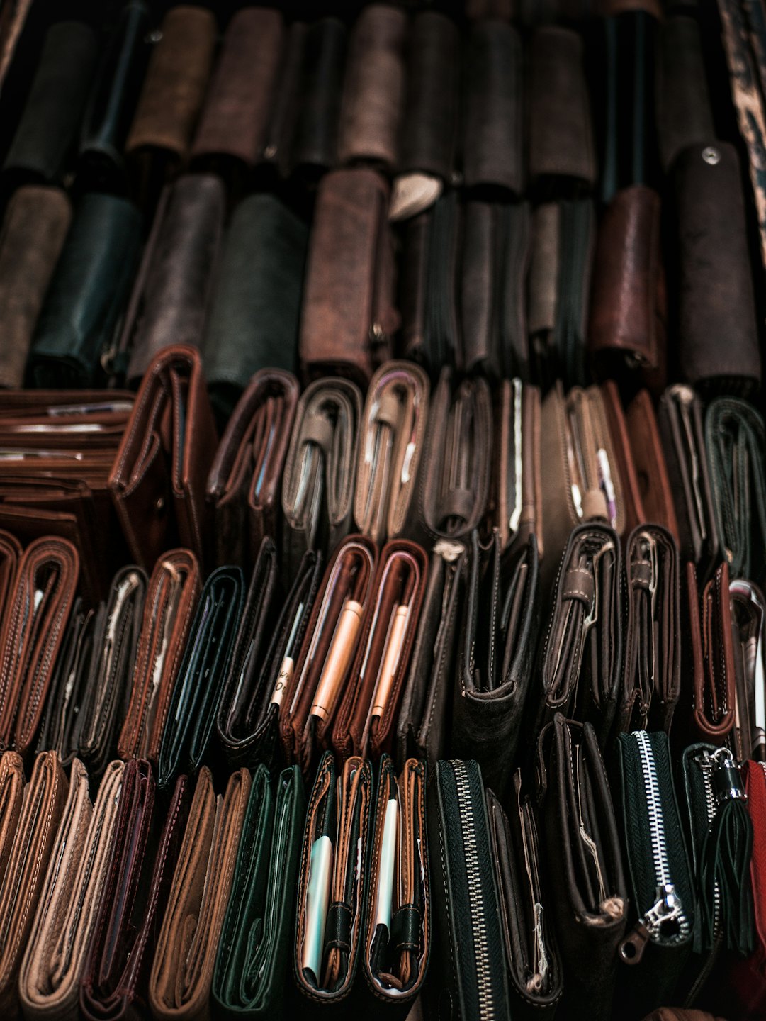 Filas de carteras de cuero marrón y negro en exhibición para la venta.