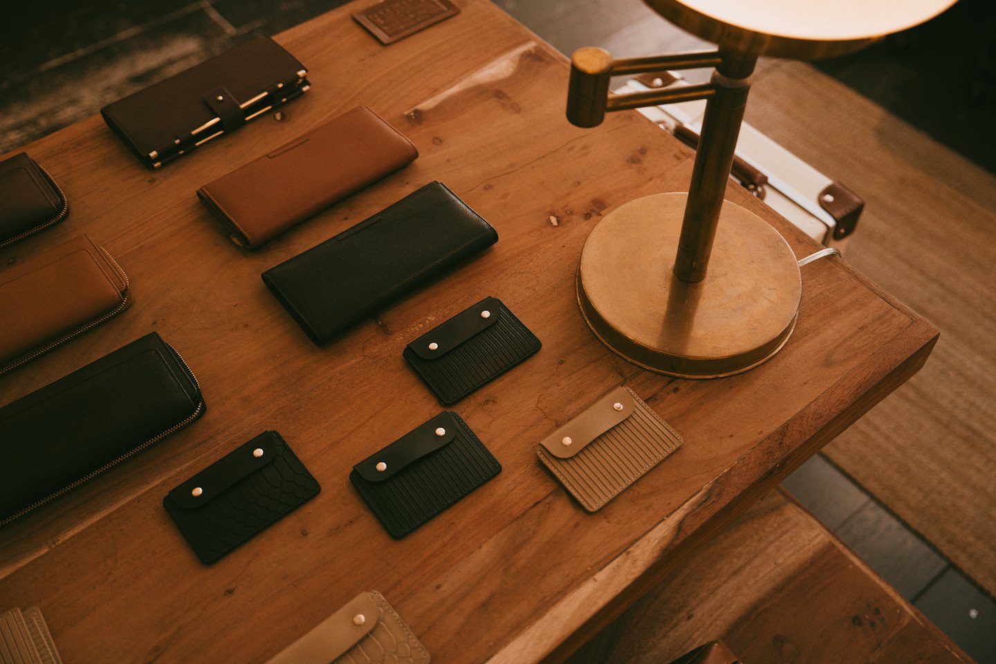 Carteras y tarjeteros de cuero expuestos sobre una mesa de madera rústica.