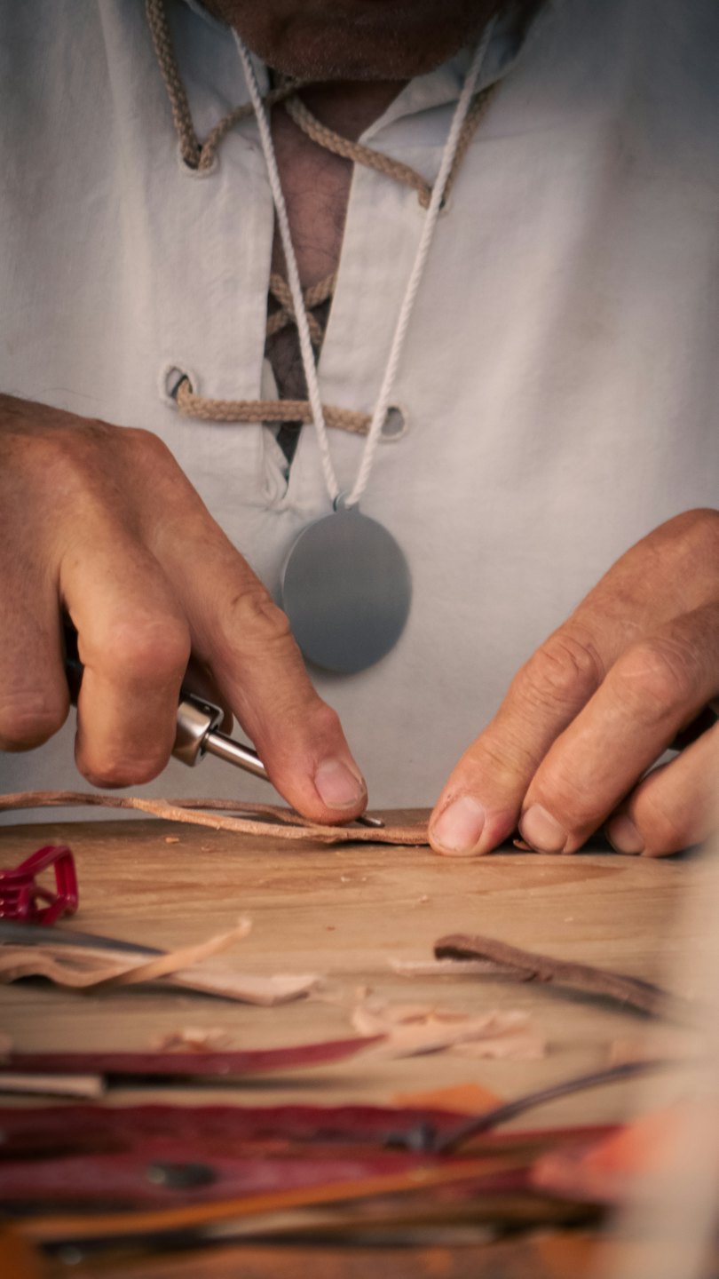 Artesano trabajando cuero con una herramienta en un taller.